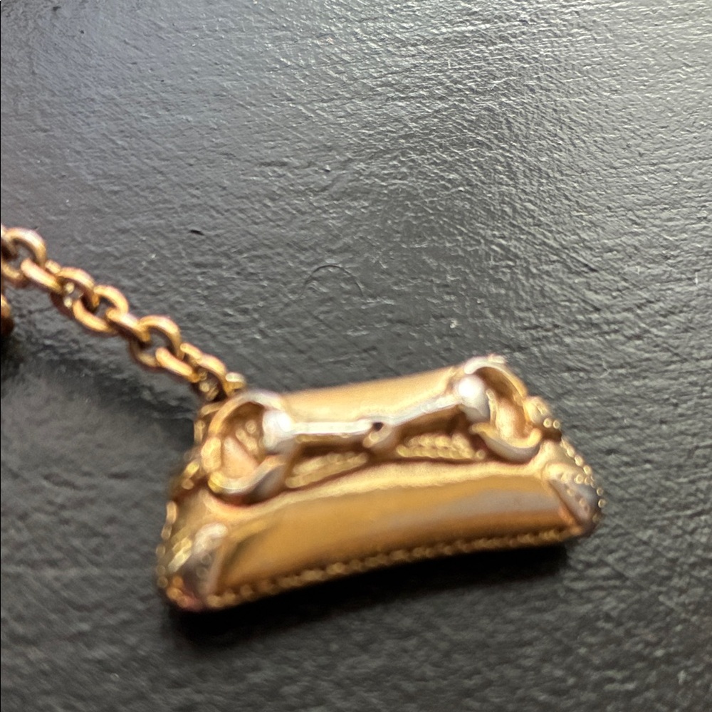 Gucci handbag charm. It’s one chain less but can be fixed.